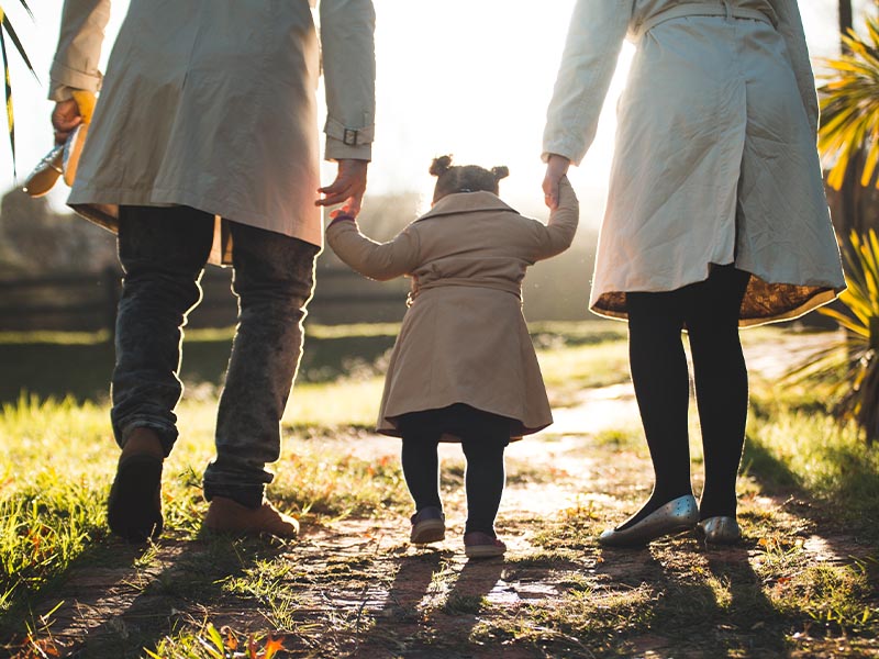 Mother and Father holding daughter's hands while walking