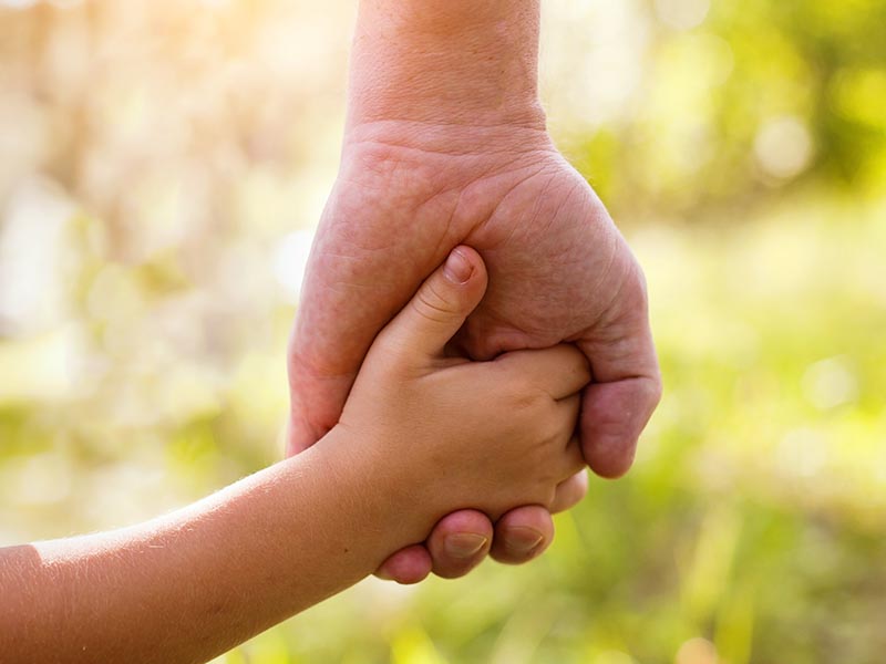 young child's hand being held by adult's hand